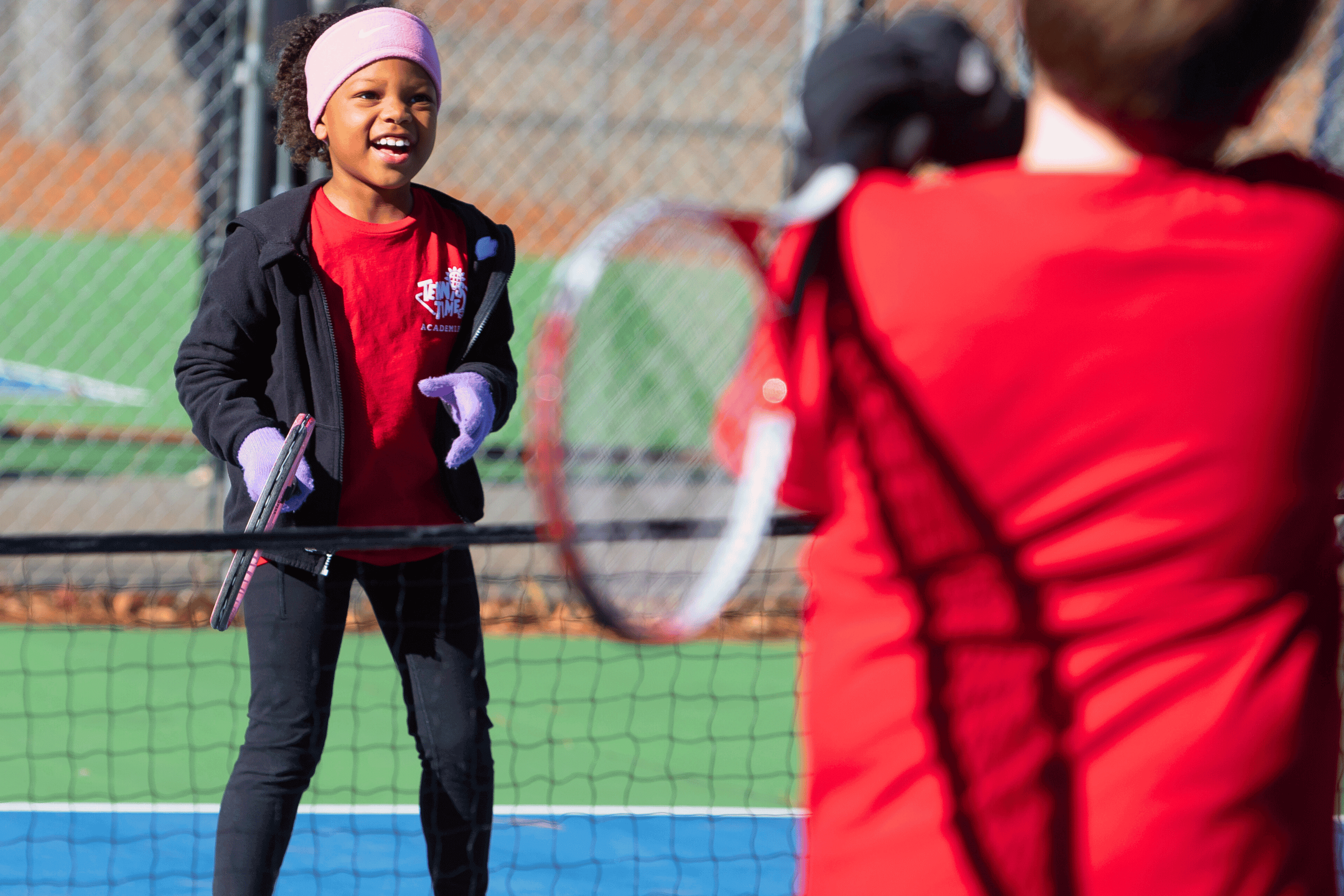 Two kids practicing tennis on a strategy court at Tennis Time Academies, learning teamwork, skills, and confidence in a fun and engaging environment.