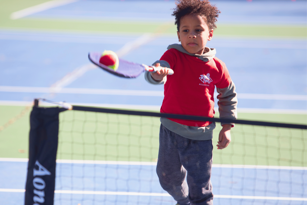 A young child in a Tennis Time Academies class using a SMART Racket to build tennis skills, designed for kids aged 5-6 to develop coordination and confidence through fun and engaging lessons.