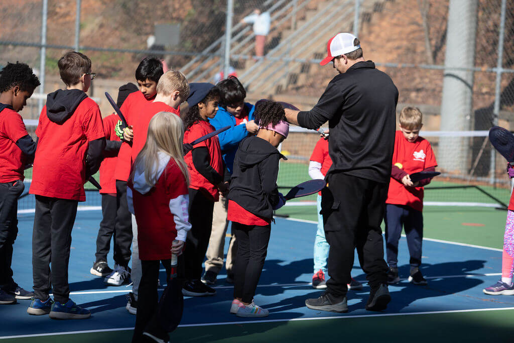 volunteer youth tennis coach teaching kids tennis