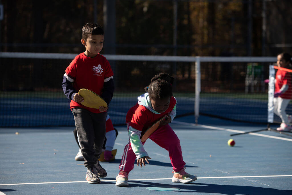 two young children playing during tennis training