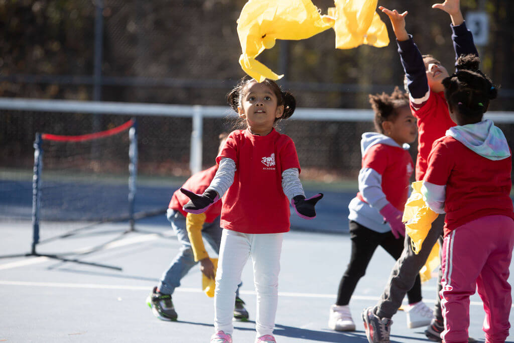 a young child playing a flying fox during the tennis training