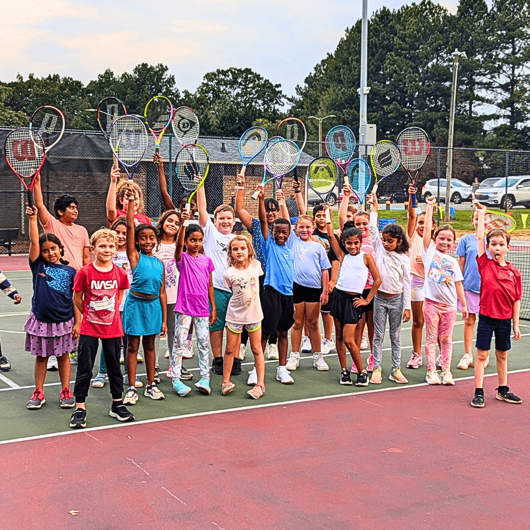 kids posing with their tennis rackets in the air at a fun summer tennis camp in Mint Hill