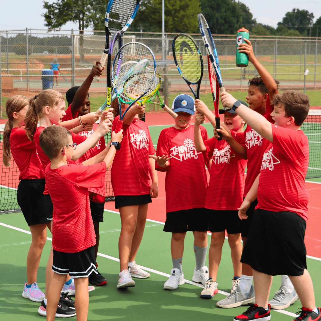 A small group of kids smiling with rackets after a fun practice session