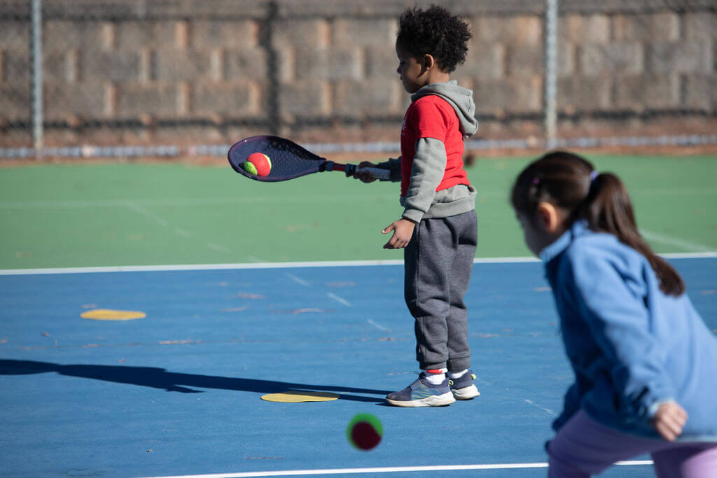 Child practicing ball control using the SMART Tennis® method—balancing a ball on the racket to build coordination, focus, and foundational technique.