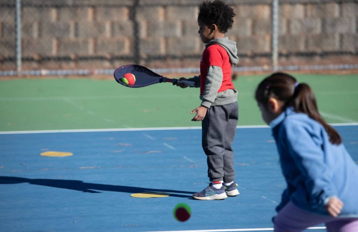Child practicing ball control using the SMART Tennis® method—balancing a ball on the racket to build coordination, focus, and foundational technique.