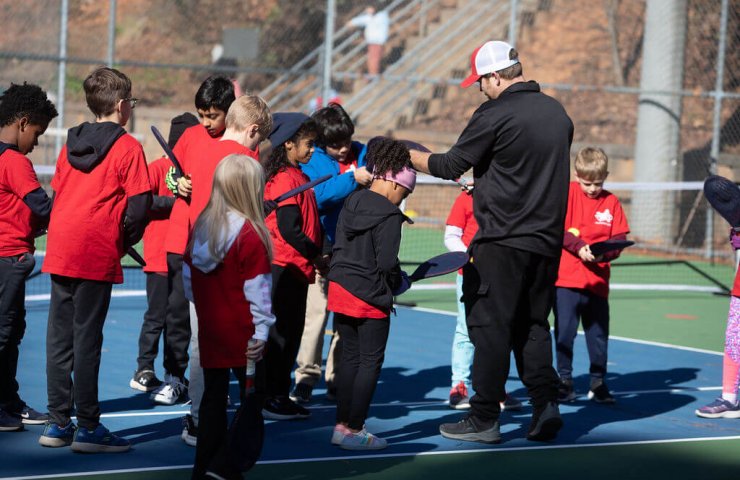 volunteer youth tennis coach teaching kids tennis