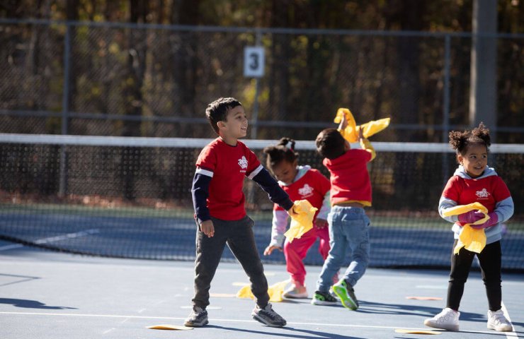 Kids playing a fun movement game on a tennis court during a Tennis Time class.