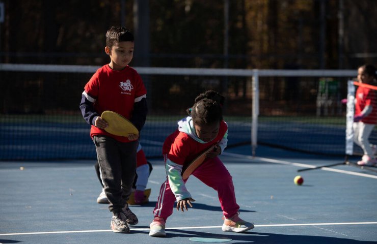 two young children playing during tennis training