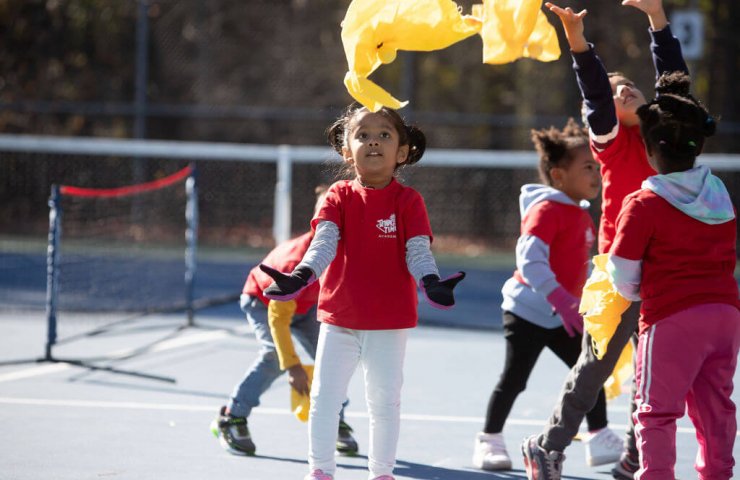 a young child playing a flying fox during the tennis training