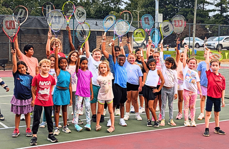 kids posing with their tennis rackets in the air at a fun summer tennis camp in Mint Hill