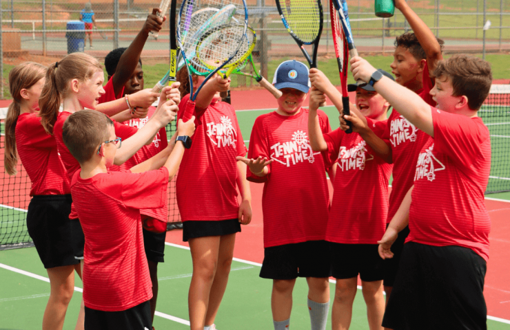 A small group of kids smiling with rackets after a fun practice session
